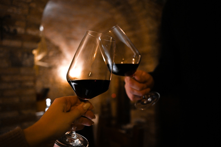 Two people toasting with glasses of red wine.