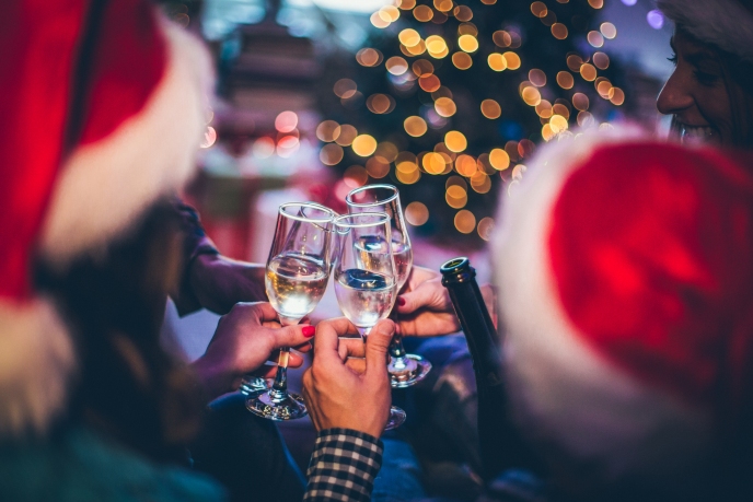 A group of people wearing Christmas hats clinking glasses of Champagne